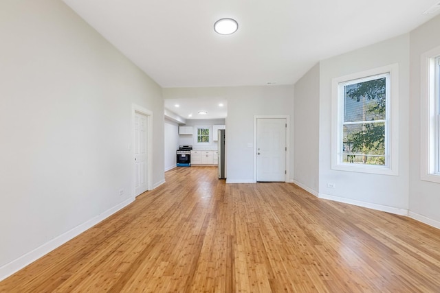 unfurnished living room featuring baseboards, a healthy amount of sunlight, light wood finished floors, and recessed lighting