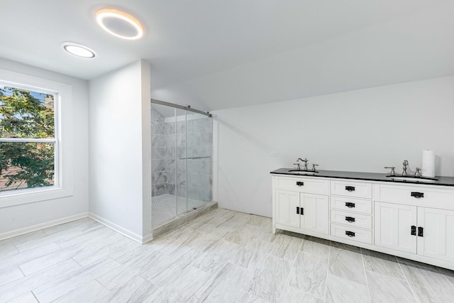 full bathroom featuring baseboards, double vanity, a stall shower, and a sink