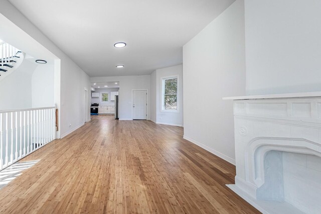 unfurnished living room featuring recessed lighting, light wood-style flooring, and baseboards
