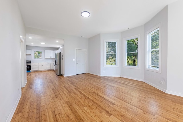 unfurnished living room with light wood finished floors, baseboards, and recessed lighting
