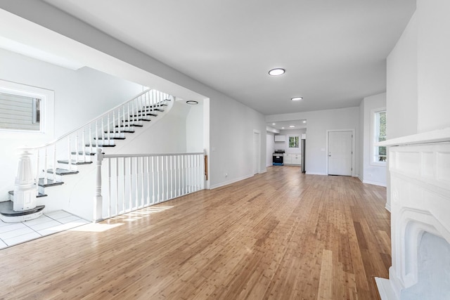 unfurnished living room with recessed lighting, wood finished floors, baseboards, and stairs