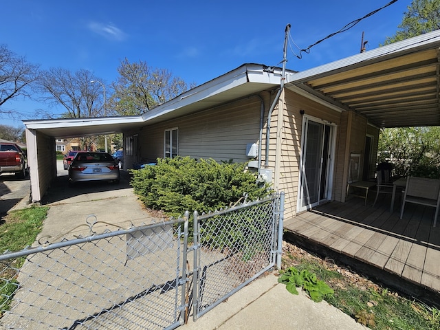 view of property exterior with concrete driveway, fence, a wooden deck, and a gate