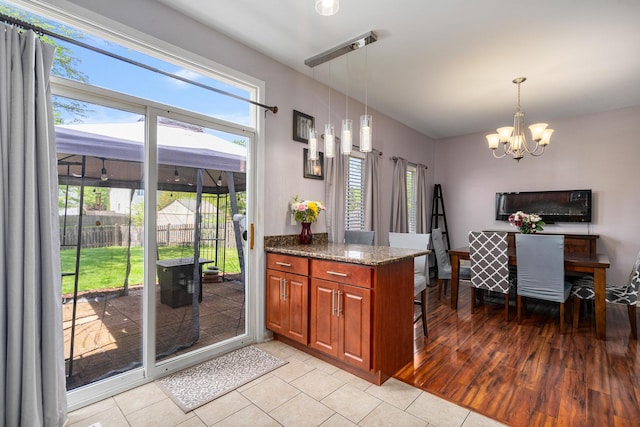 2743 River Bend Ln, Plainfield, IL 60586 - kitchen featuring a chandelier, dark stone countertops, brown cabinets, and plenty of natural light