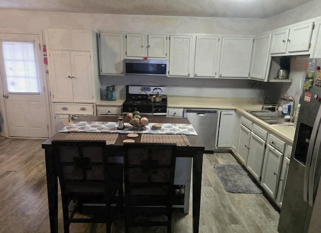 519 Greenwood Dr, Round Lake Park, IL 60073 - kitchen with appliances with stainless steel finishes, wood finished floors, light countertops, a kitchen breakfast bar, and a center island