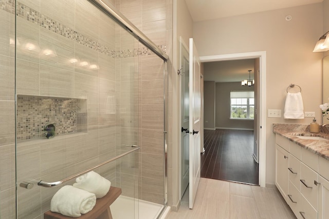 2701 Commons Dr Unit 409, Glenview, IL 60026 - full bathroom with a stall shower, vanity, baseboards, and a chandelier