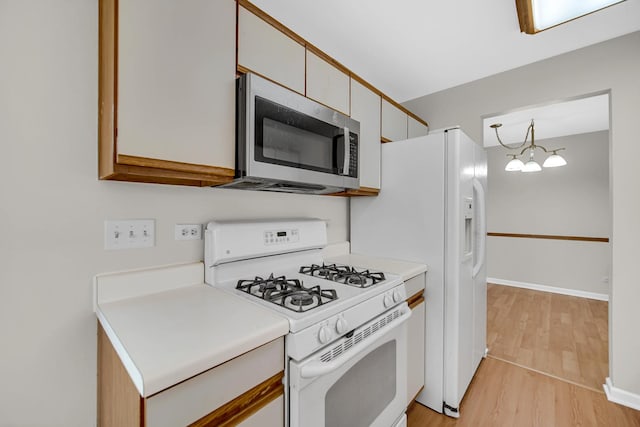 329 Pembroke Ct Unit 5, Schaumburg, IL 60193 - kitchen with white gas range oven, stainless steel microwave, light wood finished floors, light countertops, and a chandelier