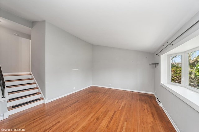 unfurnished room with wood finished floors, baseboards, and stairs