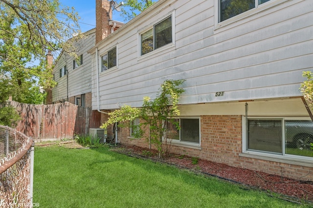view of side of home with a chimney, central AC, and brick siding