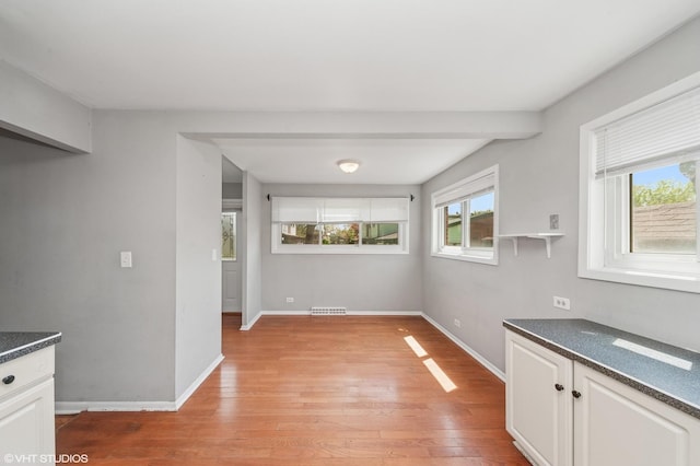 unfurnished dining area with healthy amount of natural light, light wood-type flooring, and baseboards