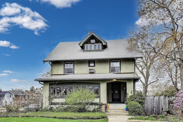american foursquare style home featuring roof with shingles, stucco siding, and fence