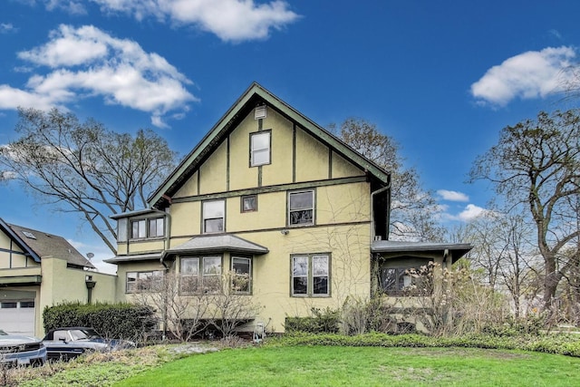 rear view of property featuring a yard and stucco siding