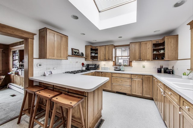 kitchen featuring a peninsula, a kitchen breakfast bar, a sink, a skylight, and open shelves