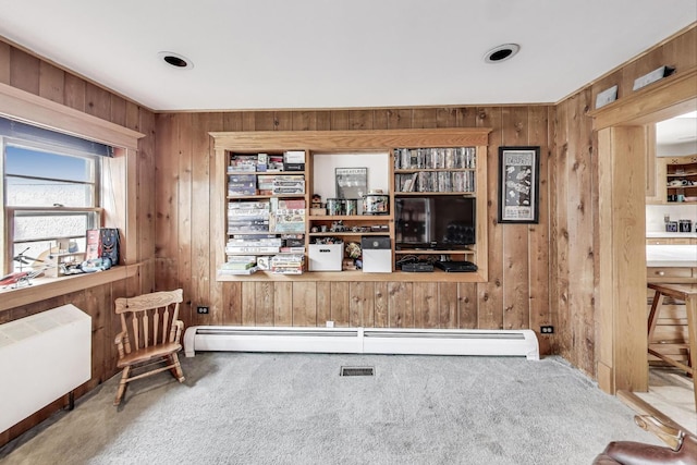 living area featuring baseboard heating, radiator, carpet floors, and wooden walls