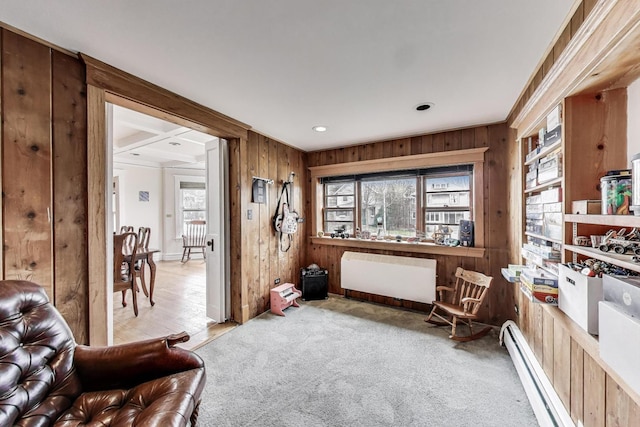sitting room with a baseboard radiator, wood walls, ornamental molding, and carpet flooring