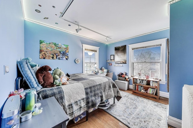 bedroom featuring track lighting, baseboards, wood finished floors, and attic access