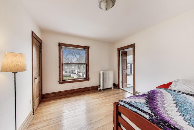 bedroom featuring radiator heating unit, baseboards, and light wood-type flooring