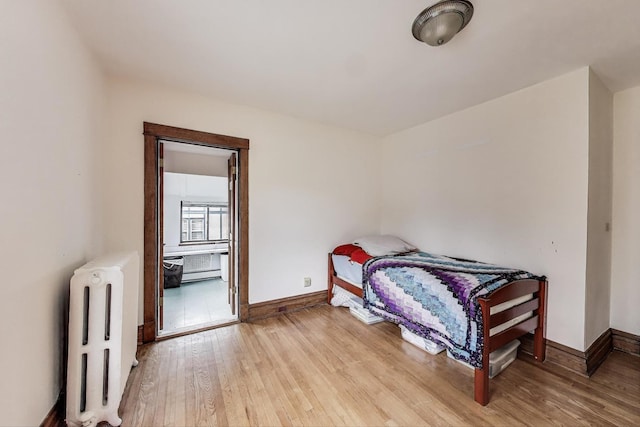 bedroom featuring radiator heating unit, baseboards, and light wood-type flooring
