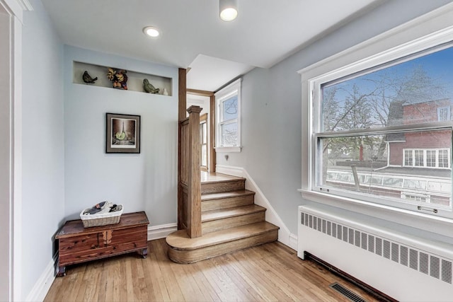 stairs with radiator heating unit, hardwood / wood-style flooring, baseboards, and recessed lighting