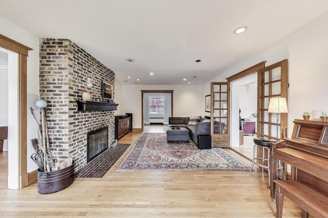 living area featuring recessed lighting, french doors, wood finished floors, and a fireplace