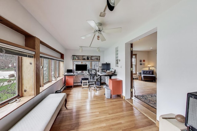 office space with built in study area, light wood-style flooring, and a ceiling fan
