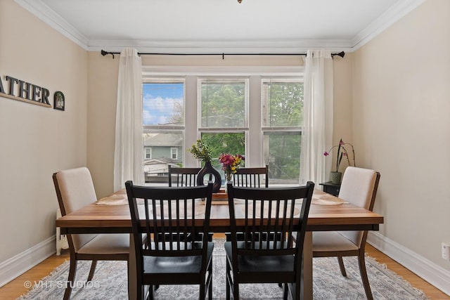 dining space featuring baseboards, ornamental molding, and light wood finished floors