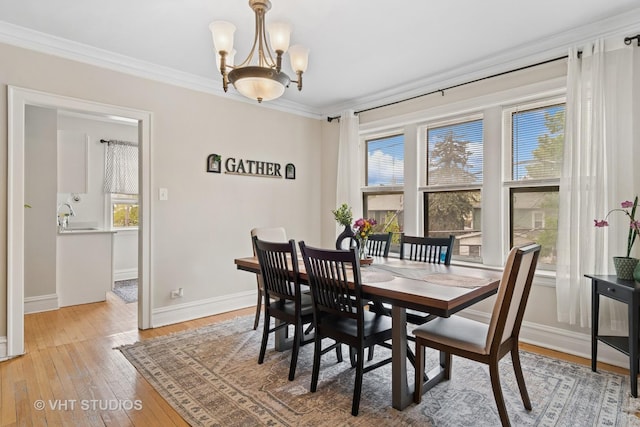 dining area featuring light wood-style floors, baseboards, an inviting chandelier, and crown molding