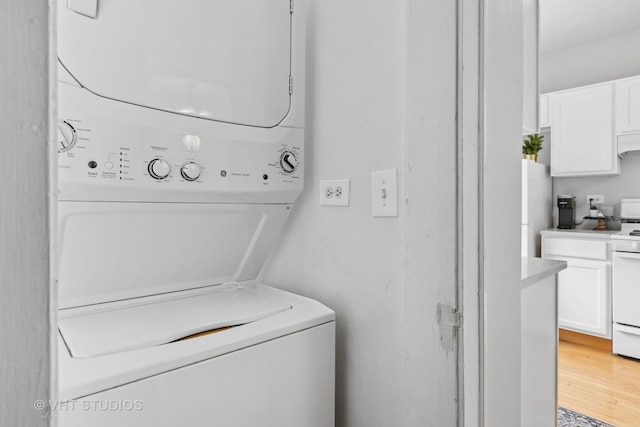 laundry area with laundry area, light wood finished floors, and stacked washer / dryer