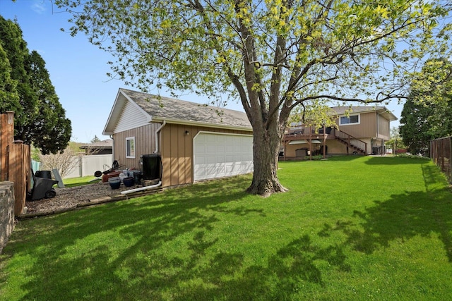 view of yard with a garage, fence, and stairway