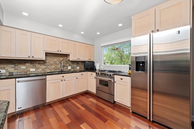 kitchen featuring appliances with stainless steel finishes, a sink, recessed lighting, decorative backsplash, and dark wood-type flooring