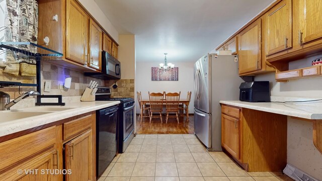9125 W 144th Pl, Orland Park, IL 60462 - kitchen with black appliances, brown cabinetry, a chandelier, and decorative backsplash