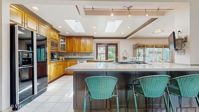 270 Concord Dr, Melrose Park, IL 60160 - kitchen with appliances with stainless steel finishes, a skylight, a breakfast bar area, light countertops, and recessed lighting