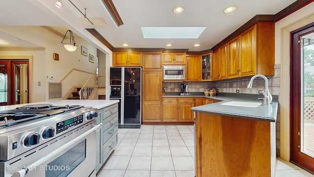 270 Concord Dr, Melrose Park, IL 60160 - kitchen with appliances with stainless steel finishes, a skylight, brown cabinets, backsplash, and light tile patterned floors