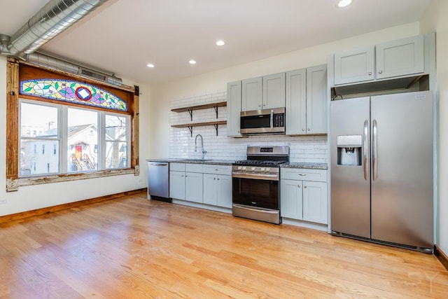 2625 W Cullerton St, Chicago, IL 60608 - kitchen with light wood finished floors, a sink, decorative backsplash, open shelves, and appliances with stainless steel finishes