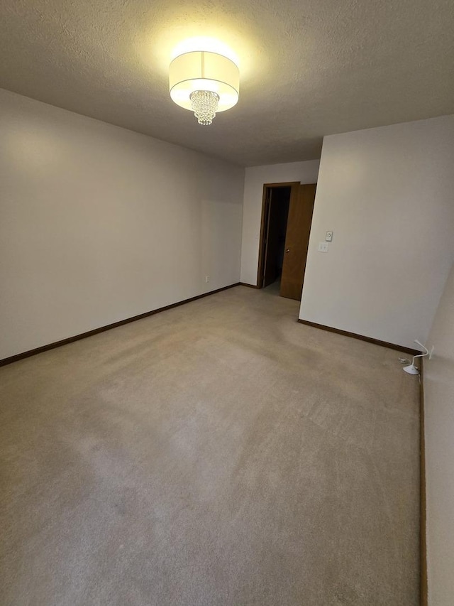 unfurnished room with a textured ceiling, baseboards, and light carpet