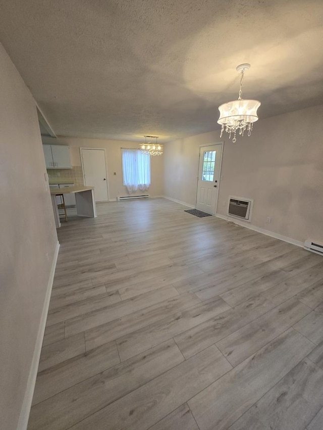interior space with a chandelier, wood finished floors, a textured ceiling, and baseboards