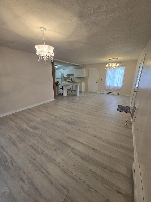 unfurnished dining area featuring baseboard heating, a baseboard heating unit, a notable chandelier, and a textured ceiling