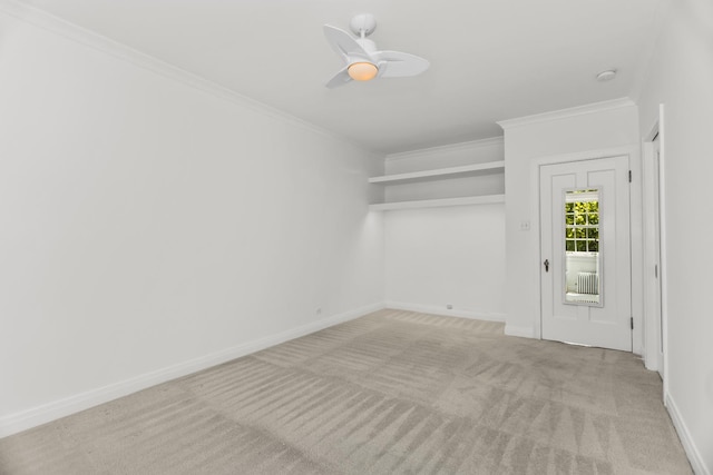 empty room featuring light colored carpet, crown molding, a ceiling fan, and baseboards