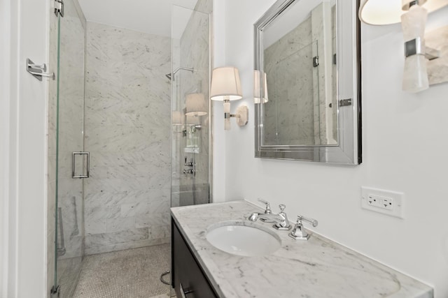full bath with a marble finish shower and vanity