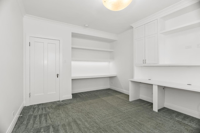 unfurnished office featuring dark colored carpet, crown molding, and baseboards