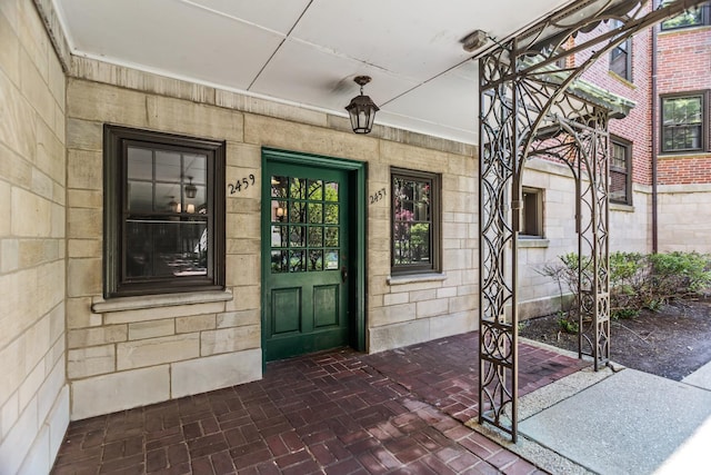 view of exterior entry with stone siding and covered porch