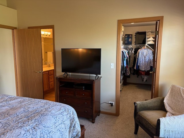 bedroom featuring carpet flooring, a walk in closet, ensuite bath, baseboards, and a closet