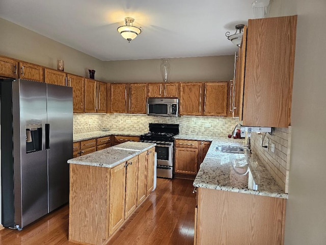 kitchen with a kitchen island, stainless steel appliances, light stone countertops, and dark wood-style floors