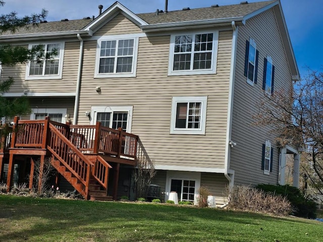 back of property featuring a lawn, a deck, and stairway
