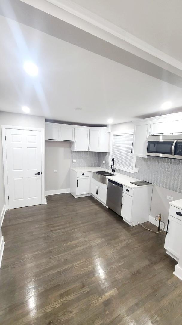 15562 Gouwens Ln, South Holland, IL 60473 - kitchen featuring white cabinets, stainless steel appliances, a sink, dark wood finished floors, and decorative backsplash