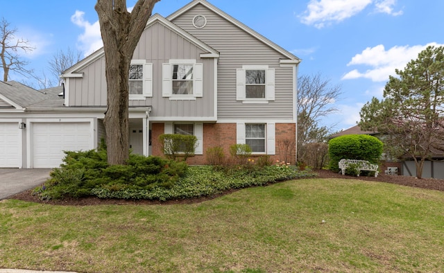 view of front of home with board and batten siding, a garage, brick siding, a front yard, and asphalt driveway