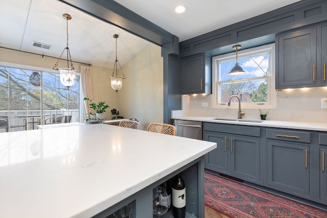 kitchen with a sink, healthy amount of natural light, dishwasher, vaulted ceiling, and pendant lighting