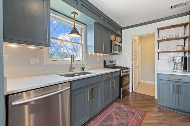 kitchen featuring appliances with stainless steel finishes, a sink, decorative backsplash, and light countertops