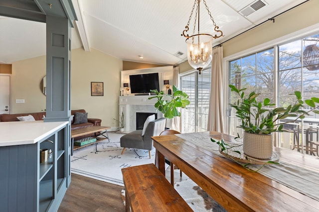dining area featuring dark wood finished floors, a high end fireplace, and a chandelier