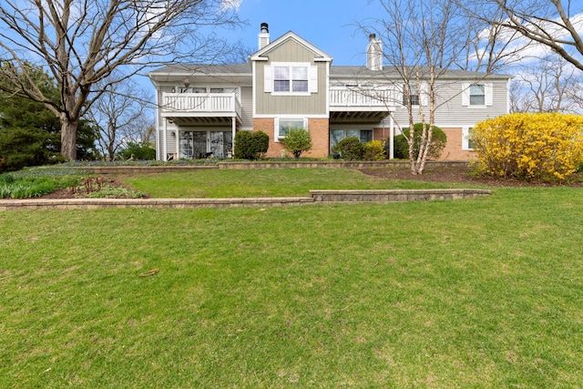 view of front of house featuring brick siding, a chimney, and a front yard