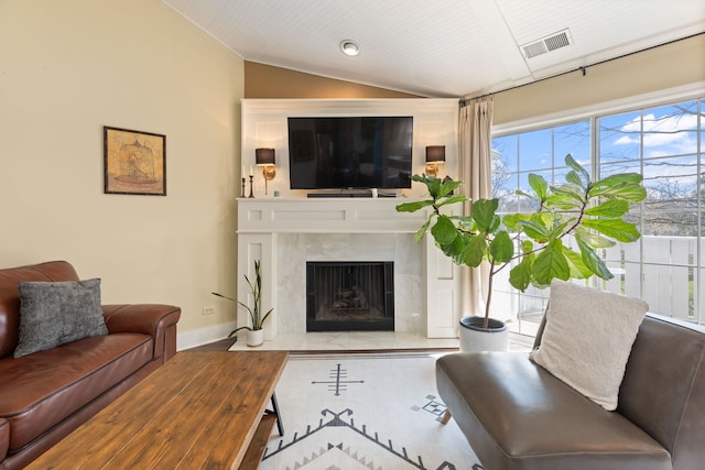 living area with vaulted ceiling, baseboards, and a premium fireplace